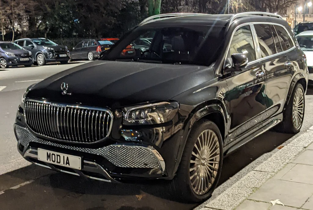 Dark Mercedes-Maybach GLS 600 parked beside a sidewalk at night