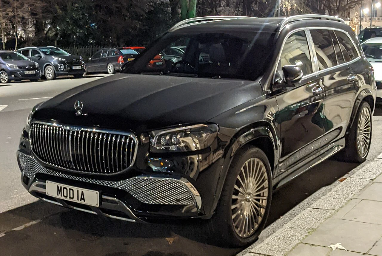 Dark Mercedes-Maybach GLS 600 parked beside a sidewalk at night