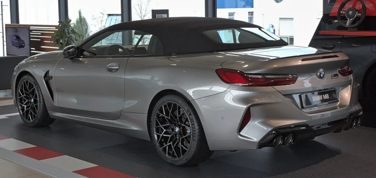 Rear three-quarter view of a gray BMW M8 Convertible with its fabric roof raised