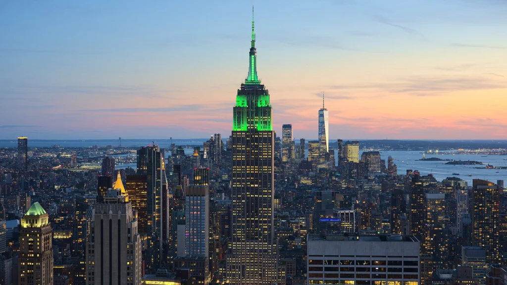 Empire State Building illuminated green above the Manhattan skyline at dusk